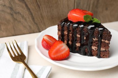 Çilek ve çatalla servis edilen çikolatalı kek, yakın plan.