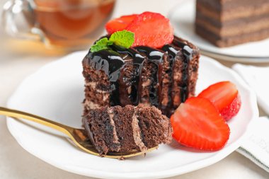 Çilek ve kaşıkla servis edilen bir parça çikolatalı pasta, yakın plan.