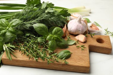 Beyaz masada farklı taze otlar ve baharatlar, yakın plan.