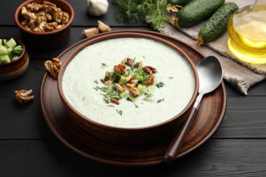 Siyah ahşap masada servis edilen dereotlu ve cevizli lezzetli salatalık çorbası.