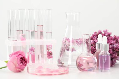 Lüks parfüm yapıyorum. Temel yağlar cam eşyalar ve çiçekler beyaz masada, yakın plan.