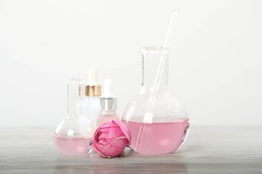 Lüks parfüm yapıyorum. Temel yağlar cam süslemede ve çiçekler beyaz ahşap masada, yakın plan.