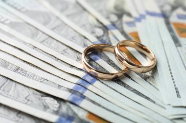 Dolar banknotları üzerinde iki altın alyans, yakın plan.