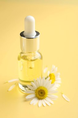 Sarı arka planda gerekli yağ ve papatya çiçekleri, yakın plan.