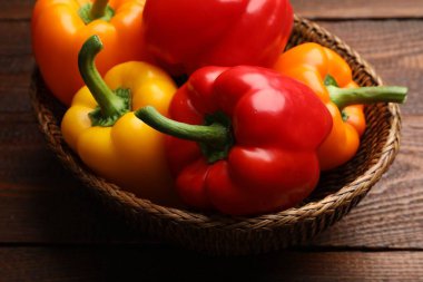 Taze renkli dolmalık biberler hasır sepetin içinde ahşap masanın üstünde, yakın plan.