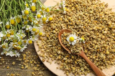 Kuru ve taze papatya çiçekleri kaşıkta masada, üst tarafta.