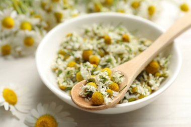 Papatya çiçekleri kasede ve kaşıkla aydınlık masada, yakın plan.