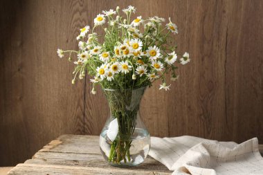 Tahta masadaki cam vazoda güzel papatya çiçekleri.