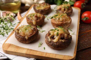 Eritilmiş peynirli lezzetli mantarlar ve ahşap masadaki kekik, yakın plan.