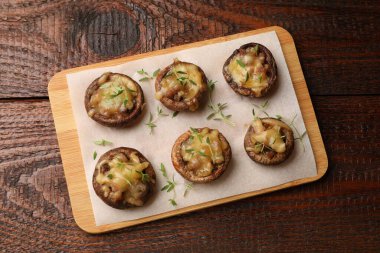 Eritilmiş peynirli lezzetli mantarlar ve ahşap masadaki kekik.