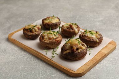 Eritilmiş peynirli lezzetli mantarlar ve gri desenli masadaki kekik, yakın plan.