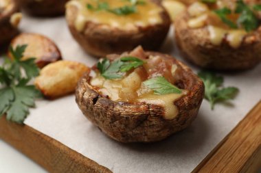 Eritilmiş peynirli ve maydanozlu lezzetli mantarlar beyaz masada, yakın plan.