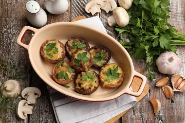 Pişirme kabında lezzetli mantarlar ve renkli ahşap masa üzerinde ürünler.