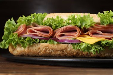 Jambonlu, peynirli ve sebzeli baget sandviç. Ahşap masa, siyah arka plan, yakın plan.