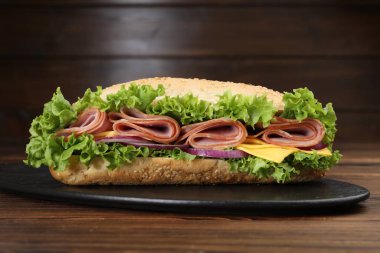 Jambonlu, peynirli ve sebzeli baget sandviç kahverengi arka planda, yakın planda.