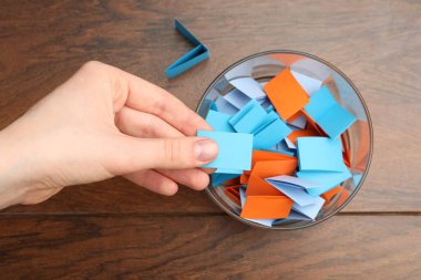 Tahta masadaki kavanozdan kağıt alan kadın, üst manzara.