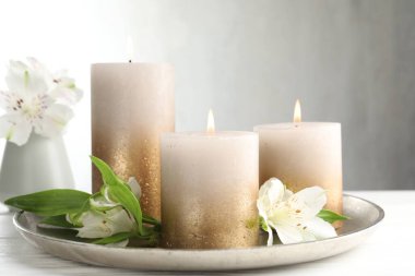 Beyaz masada yanan mumlar ve güzel çiçekler.