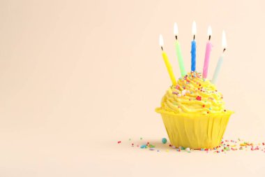 Burning candles in cupcake and sprinkles on beige background, space for text