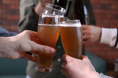 Arkadaşlar bira bardaklarını tokuşturur, yakın plan