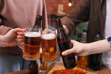 Arkadaşlar bira bardaklarını tokuşturur, yakın plan