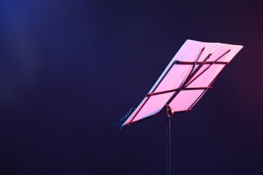 Koyu arka planda neon lambalarla müzik kağıtlarıyla durun, yakın plan. Metin için boşluk