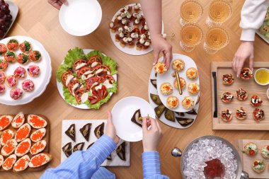 Açık büfe menüsü. İnsanlar ahşap masadan lezzetli aperatifler alıyor.