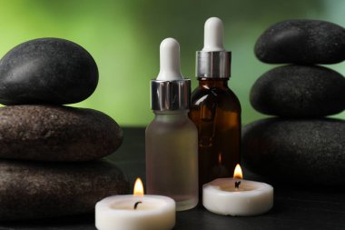 Taşlar, damlalar ve yanan mumlar ile kaplıca bileşimi koyu yeşil arka planda, yakın plan