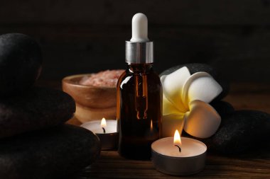 Taşlar, damlalar ve yanan mumlarla kaplıca kompozisyonu siyah arka planda, yakın plan