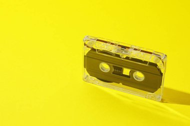 Sarı arka planda manyetik bantlı bir ses kaseti, yakın plan. Metin için boşluk