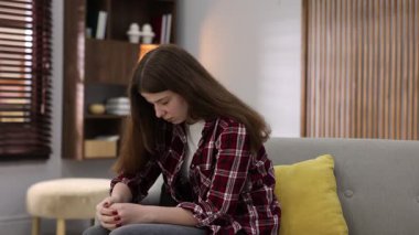 Evdeki kanepede endişeli bir genç kız.