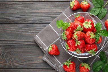 Taze olgun çilekler ve yapraklar siyah ahşap masada, düz yerde. Metin için boşluk