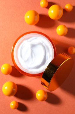 Turuncu arka planda bir kavanoz nemlendirici vücut kremi ve toplar.