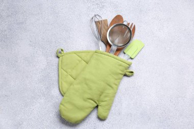 Farklı mutfak gereçleri fırın eldivenleri ışık masasında, üst görünümde.