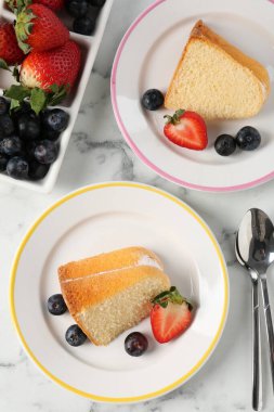 Beyaz mermer masanın üzerinde böğürtlenli lezzetli kek parçaları.