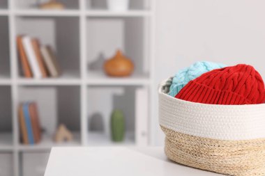 Hasır sepetteki farklı yün şapkalar beyaz masa içinde, mesaj için yer var.