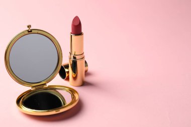 Açık cep aynası ve pembe arka planda ruj, yakın plan. Metin için boşluk