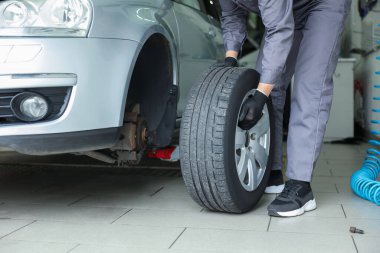 Tamirci araba servisinde lastik değiştiriyor, yakın plan.