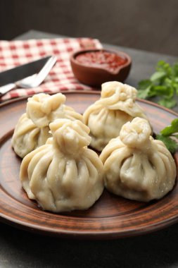 Gri masadaki sosla servis edilen lezzetli khinkali, yakın plan.