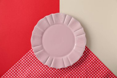 Renk arkaplanında boş bir tabak ve masa örtüsü, üst görünüm