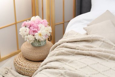 Yan masada yatağın yanında çiçekler var.