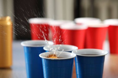 Bira pong oyunu. İçkili plastik bardaklar ve masada top, yakın plan.