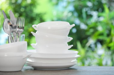 Ahşap masada, bulanık yeşil arka planda farklı temiz tabaklar.