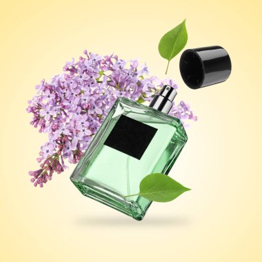 Bir şişe çiçek parfümü ve bej renkli arka planda çiçek açan leylak.