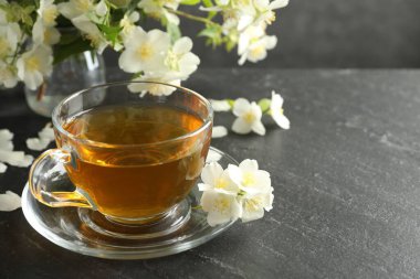 Aromatik yasemin çayı ve çiçekler gri masada, yakın plan. Metin için boşluk