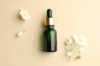 Temel yağ ve güzel yasemin çiçekleri bej arka planda, düz yatıyordu.