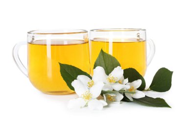 Cam fincanlar, çiçekler ve yeşil yapraklar içinde beyaz üzerine izole edilmiş yasemin çayı.