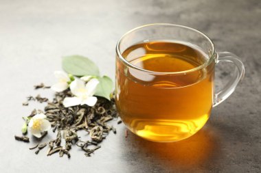 Cam bardakta Aromatik yasemin çayı, Gri masada bira ve çiçekler, yakın plan