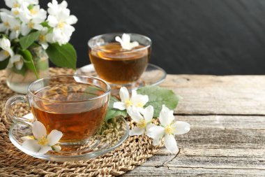 Cam bardaklarda yasemin çayı, ahşap masada çiçekler ve yeşil yapraklar, yakın plan. Metin için boşluk