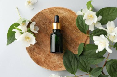 Kozmetik ürünleri ve yasemin çiçekleri beyaz arka planda, düz yatıyordu