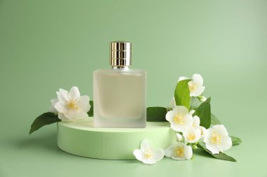 Bir şişe parfüm ve yeşil arka planda yasemin çiçekleri.
